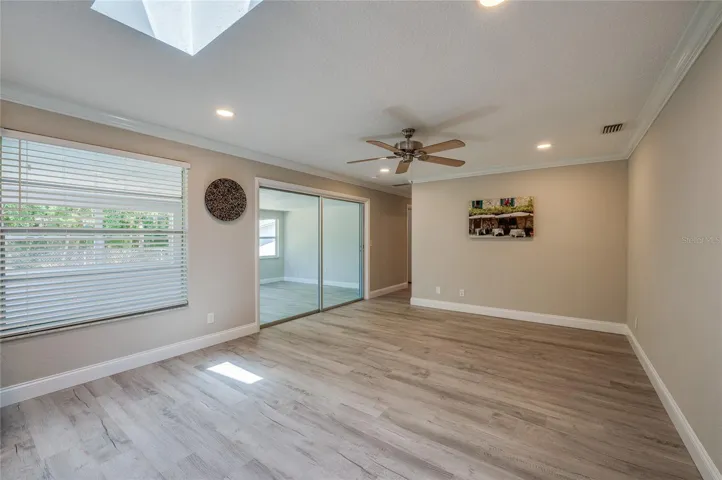 Spacious dining room featuring a skylight that adds an extra touch of brightness. Sliding glass doors lead to an adjacent sunroom, effortlessly blending indoor and outdoor elements.