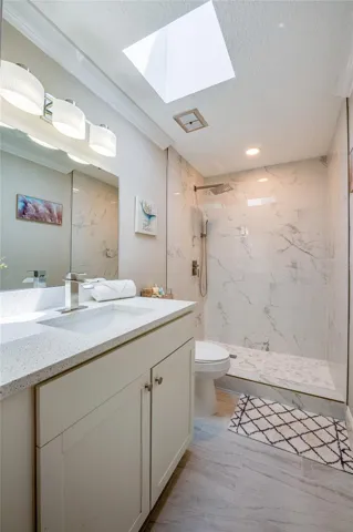Beautifully renovated bathroom featuring a chic single-sink vanity, a large walk-in tile shower, and a stunning skylight that bathes the room in sunshine.