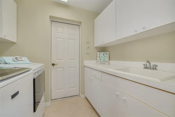 Inside laundry, with newer washer and dryer, plus a sink and plenty of cabinets!