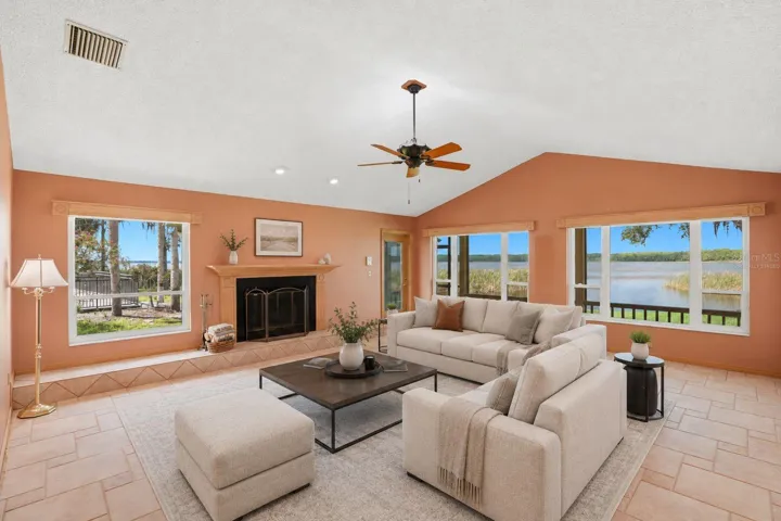 Open Family Room with woodburning fireplace andexpansive views of LakeTarpon and hurricane impactrated windows and Frenchdoors to the enclosed pool..Seamless flow to the kitchen,breakfast area, 3rd bath andpool area -virtually staged