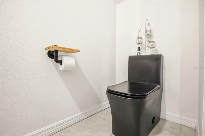 Sleek matte black commode and industrial-style hardware give this powder room a bold, modern edge.