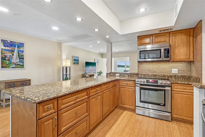 The BEAUTIFULLY UPDATED Kitchen is designed for both everyday living and entertaining, featuring GRANITE COUNTERTOPS, stainless steel appliances, abundant cabinetry, a breakfast bar, a NEW backsplash, and a NEW REFRIGERATOR.
