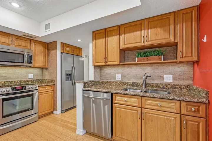 The BEAUTIFULLY UPDATED Kitchen is designed for both everyday living and entertaining, featuring GRANITE COUNTERTOPS, stainless steel appliances, abundant cabinetry, a breakfast bar, a NEW backsplash, and a NEW REFRIGERATOR.