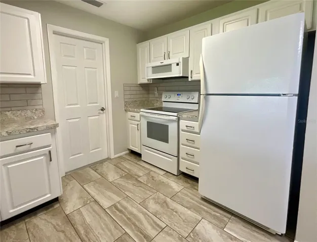 Kitchen range, refrigerator, microwave area and door to garage laundry area