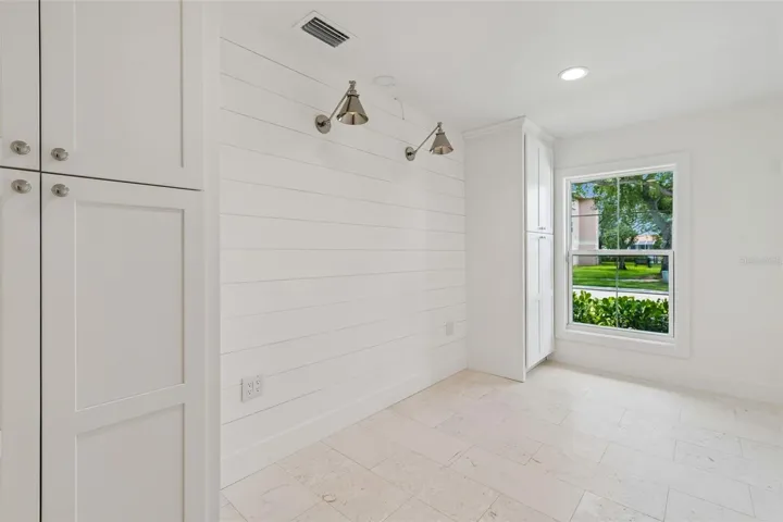 Den/office w/ shell stone tile flooring, custom cabinetry, upscale sconce & recess lighting