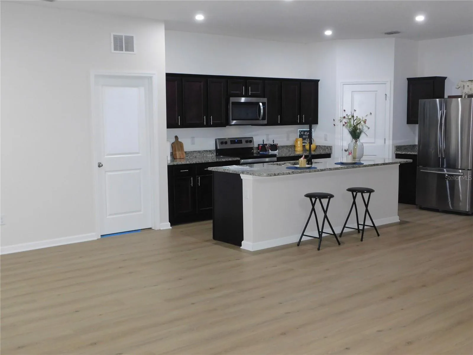 New Flooring in Large Kitchen features Oversized Granite Island Upgraded faucet and walk in pantry