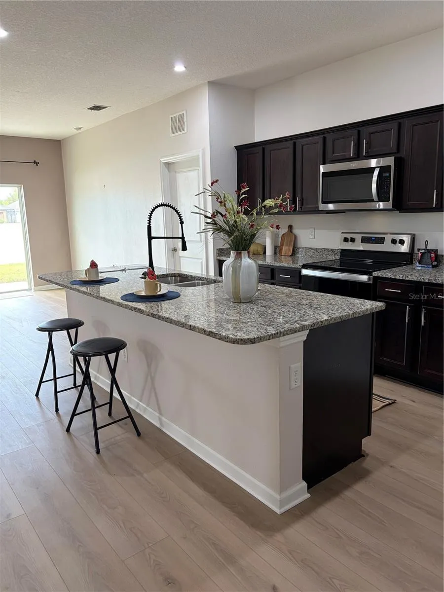 New Flooring in Large Kitchen features Oversized Granite Island Upgraded faucet and walk in pantry
