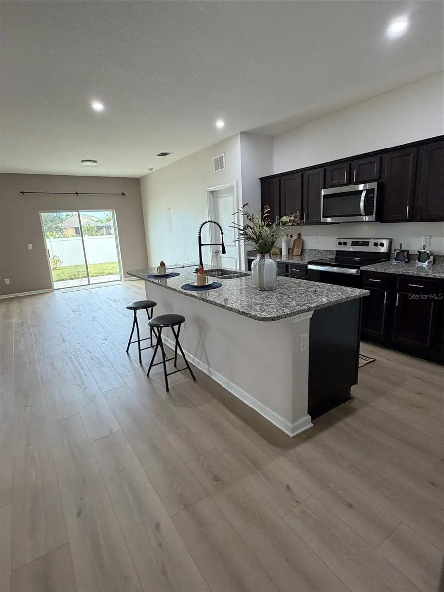 New 9X60 Flooring in Large Kitchen features Oversized Granite Island Upgraded faucet and walk in pantry