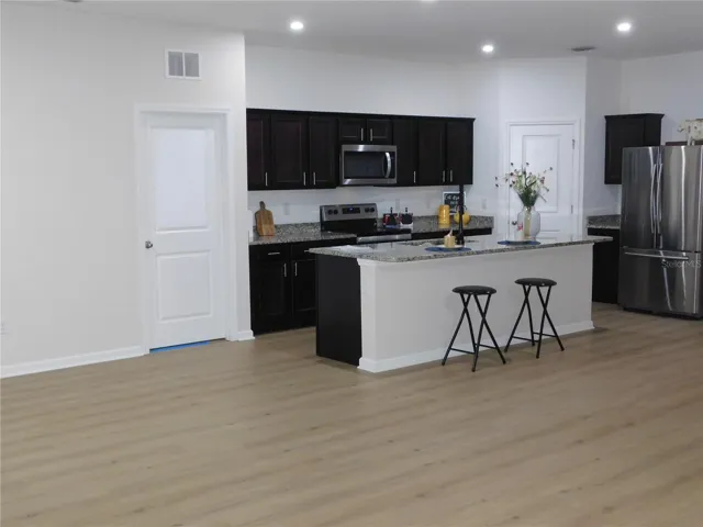 New Flooring in Large Kitchen features Oversized Granite Island Upgraded faucet and walk in pantry