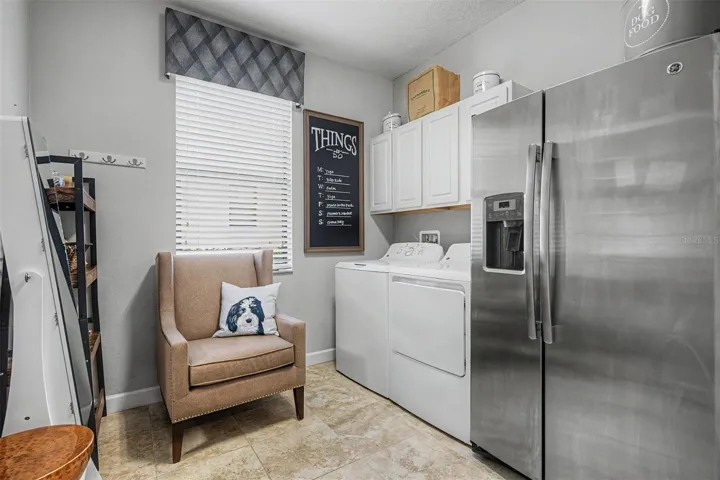 Laundry room with extra refrigerator and storage.