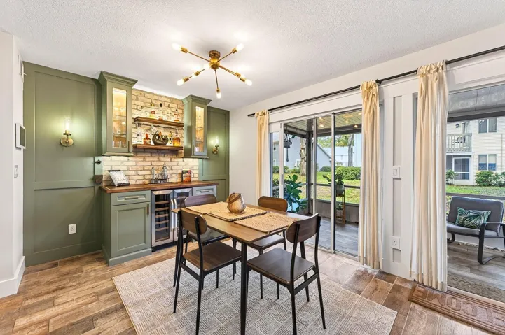 The Dining area also offers sliding doors to the patio and is accented by a CUSTOM BUILT-IN WALL FEATURE complete with cabinetry, shelving, and a stylish bar area, making entertaining both easy and elegant.