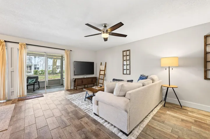 The spacious Living Room is FILLED WITH SUNLIGHT and features sliding glass doors that open to the COVERED and ENCLOSED SCREENED PATIO.