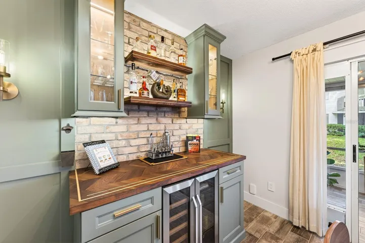 The Dining area also offers sliding doors to the patio and is accented by a CUSTOM BUILT-IN WALL FEATURE complete with cabinetry, shelving, and a stylish bar area, making entertaining both easy and elegant.