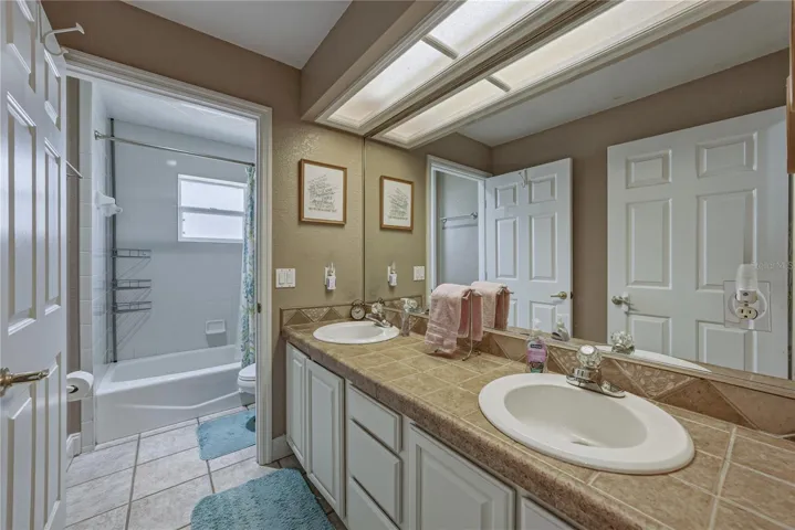 The guest bath has a tub shower combination and a vanity with 2 sinks.