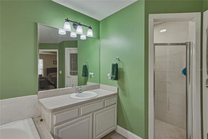 The stall shower has ceramic tile surround.
