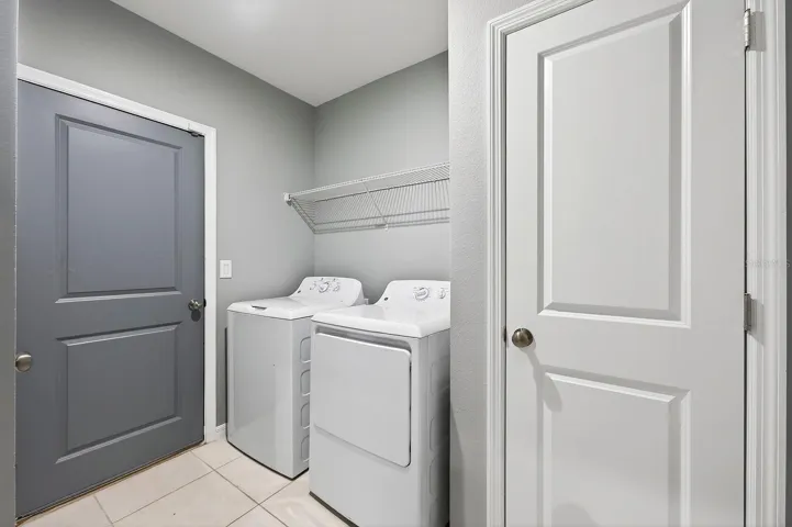 A DEDICATED LAUNDRY ROOM with shelving and a linen closet adds convenience and extra storage.
