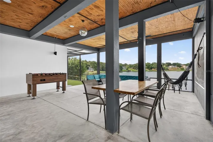 Walkout lake-level screened entertaining area with built-in bar, summer kitchen, lounge space, game area, hammock, putting green-style turf area, and views of Lake Louise.