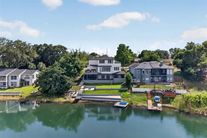 Private sandy beach area with volleyball setup, lakefront lawn, firepit, patio, two docks, and multiple outdoor entertaining spaces.