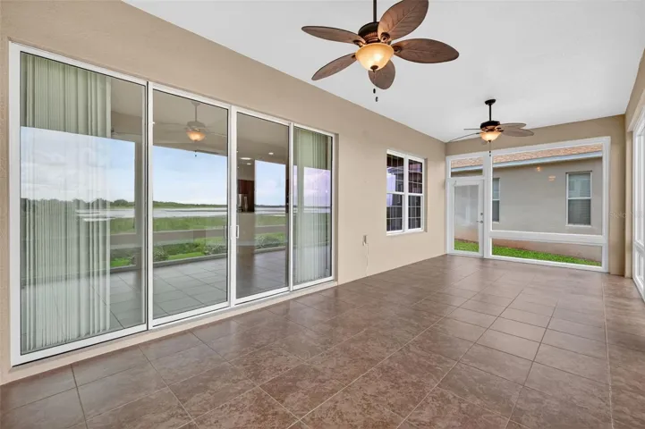 SPACIOUS GLASS ENCLOSED LANAI WITH TILE FLOORING AND CEILING FANS.