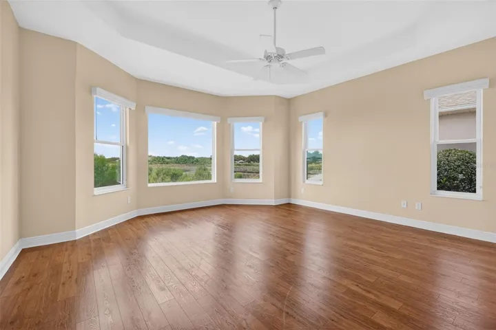 PRIMARY BEDROOM WITH LOVELY LAMINATE FLOORING, TRAY CEILING AND LARGE BAY WINDOW WITH A BREATHTAKING VIEW OF THE LAKE AND SURROUNDING AREA!