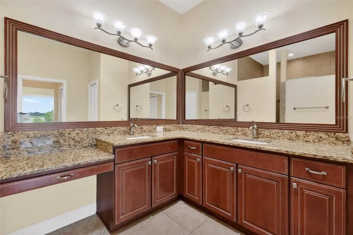 GRANITE COUNTERTOPS, CUSTOM FRAMED MIRRORS, DUAL SINKS, AND A VANITY.
