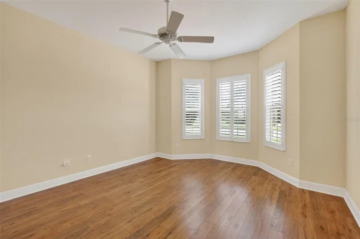 FRONT GUEST ROOM WITH BAY WINDOW, LAMINATE FLOORING, AND PLANTATION SHUTTERS.
