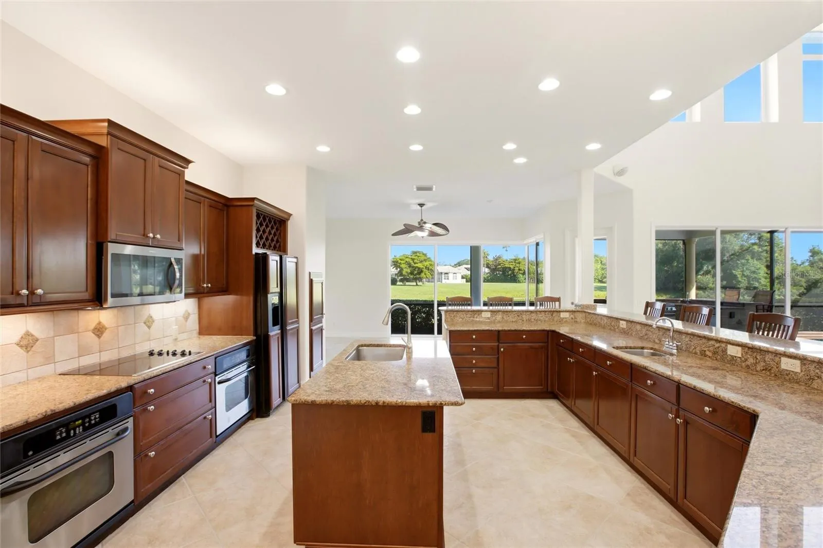 The kitchen offers an extensive breakfast bar and a comfortable casual dining area, along with generous counter space, dual sinks, double ovens, abundant cabinetry, and a spacious walk-in pantry.