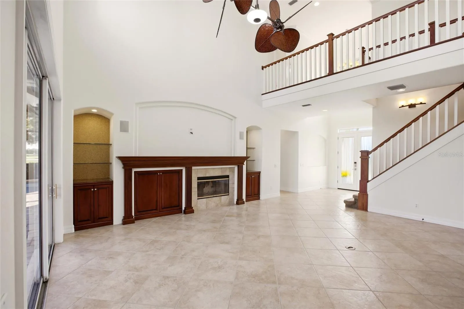 The family room features soaring cathedral ceilings, a fireplace with mantel, and sliding glass doors opening to the lanai, while flowing seamlessly into the kitchen for comfortable everyday living and entertaining.