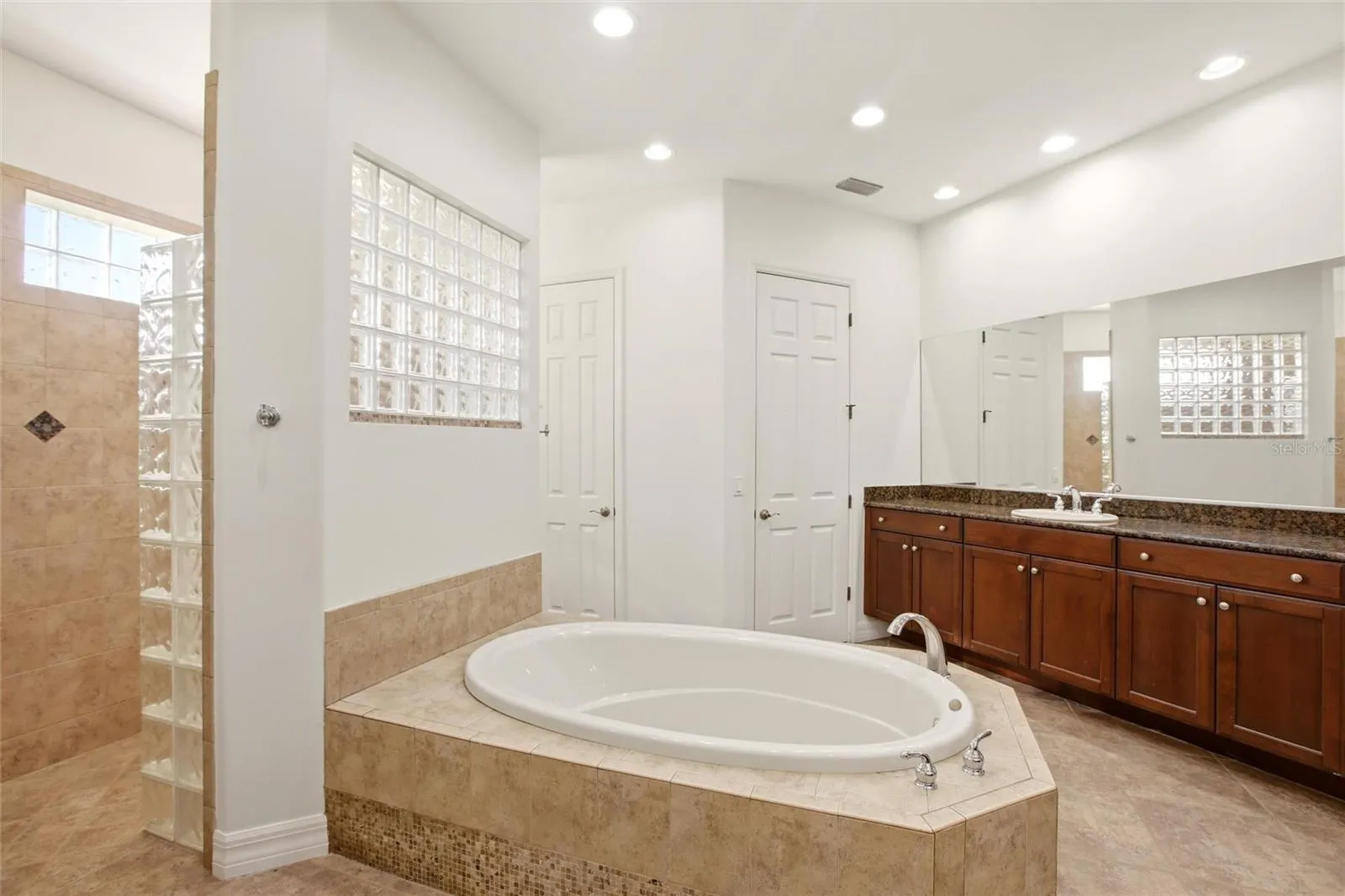 The primary bathroom features a soaking tub, split vanities with dedicated makeup counter space, a spacious walk-in shower with dual shower heads, a private water closet, and dual walk-in closets with custom organization.
