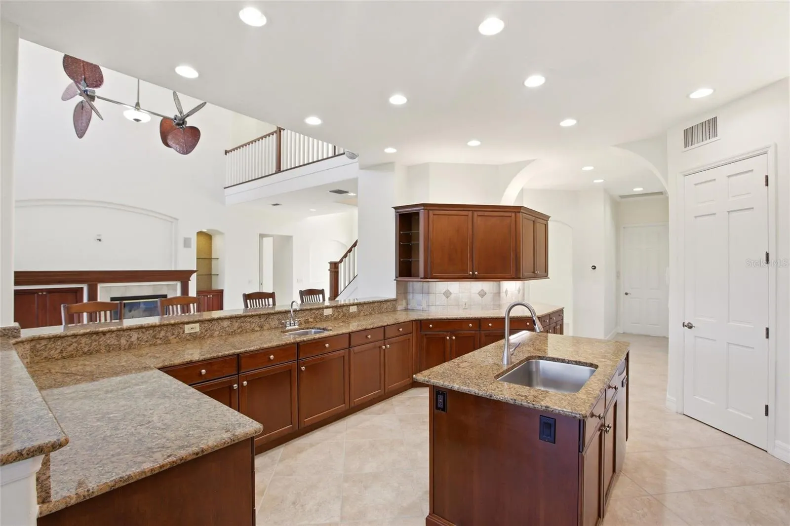 The kitchen offers an extensive breakfast bar and a comfortable casual dining area, along with generous counter space, dual sinks, double ovens, abundant cabinetry, and a spacious walk-in pantry.