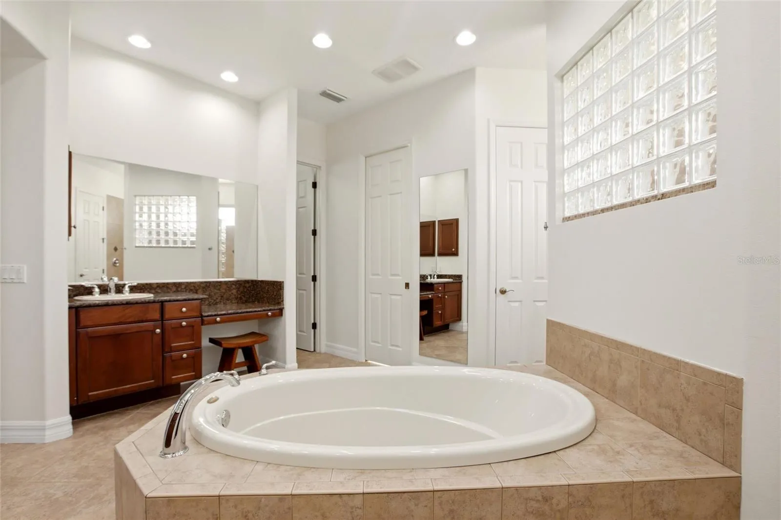 The primary bathroom features a soaking tub, split vanities with dedicated makeup counter space, a spacious walk-in shower with dual shower heads, a private water closet, and dual walk-in closets with custom organization.