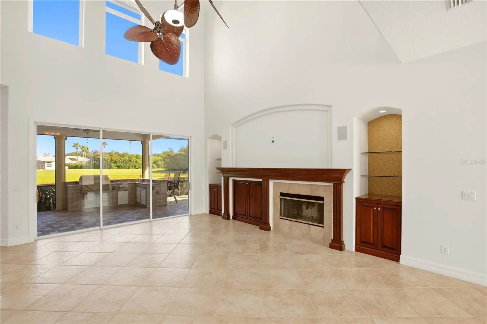 The family room features soaring cathedral ceilings, a fireplace with mantel, and sliding glass doors opening to the lanai, while flowing seamlessly into the kitchen for comfortable everyday living and entertaining.