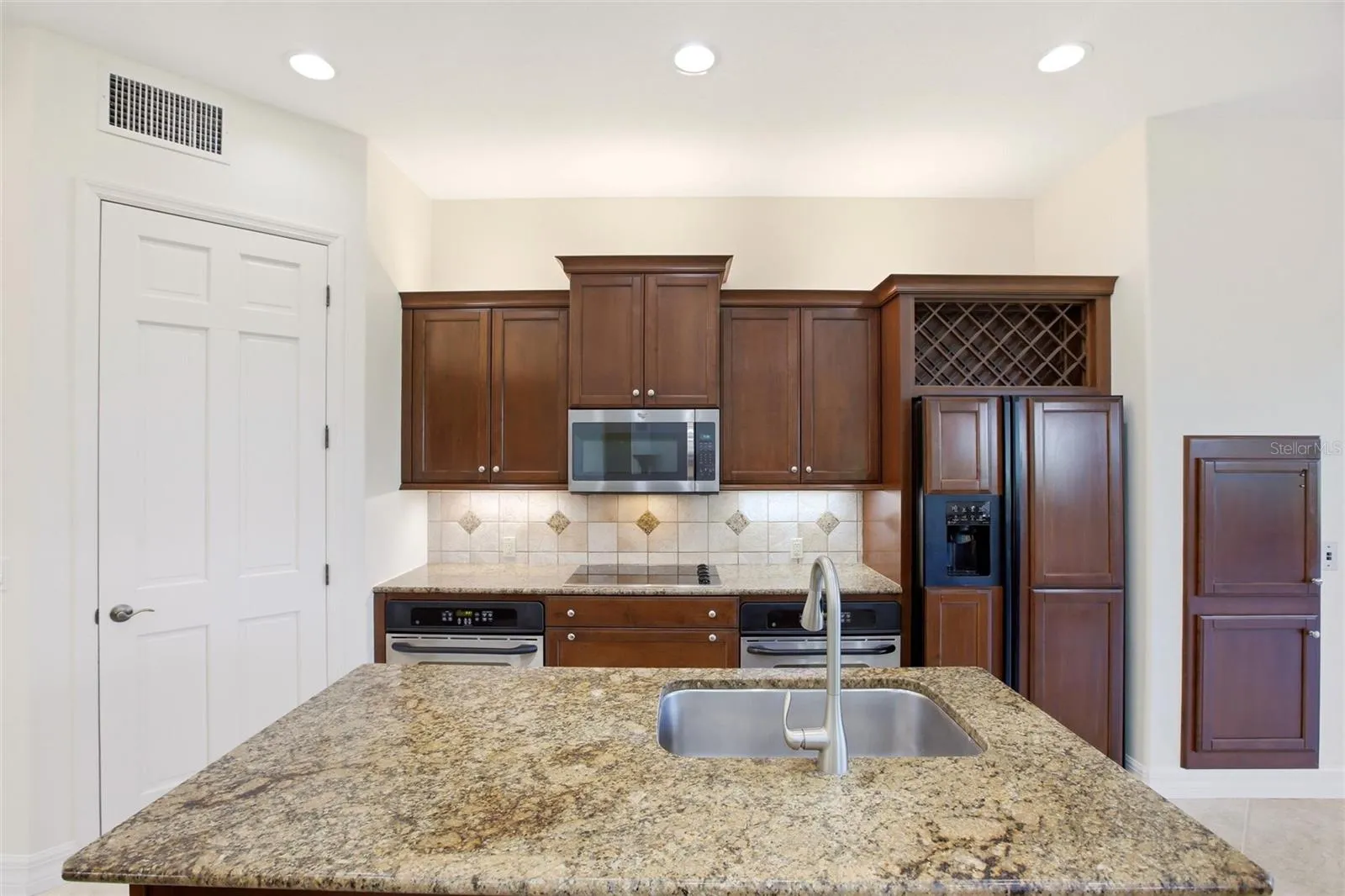 The kitchen offers an extensive breakfast bar and a comfortable casual dining area, along with generous counter space, dual sinks, double ovens, abundant cabinetry, and a spacious walk-in pantry.