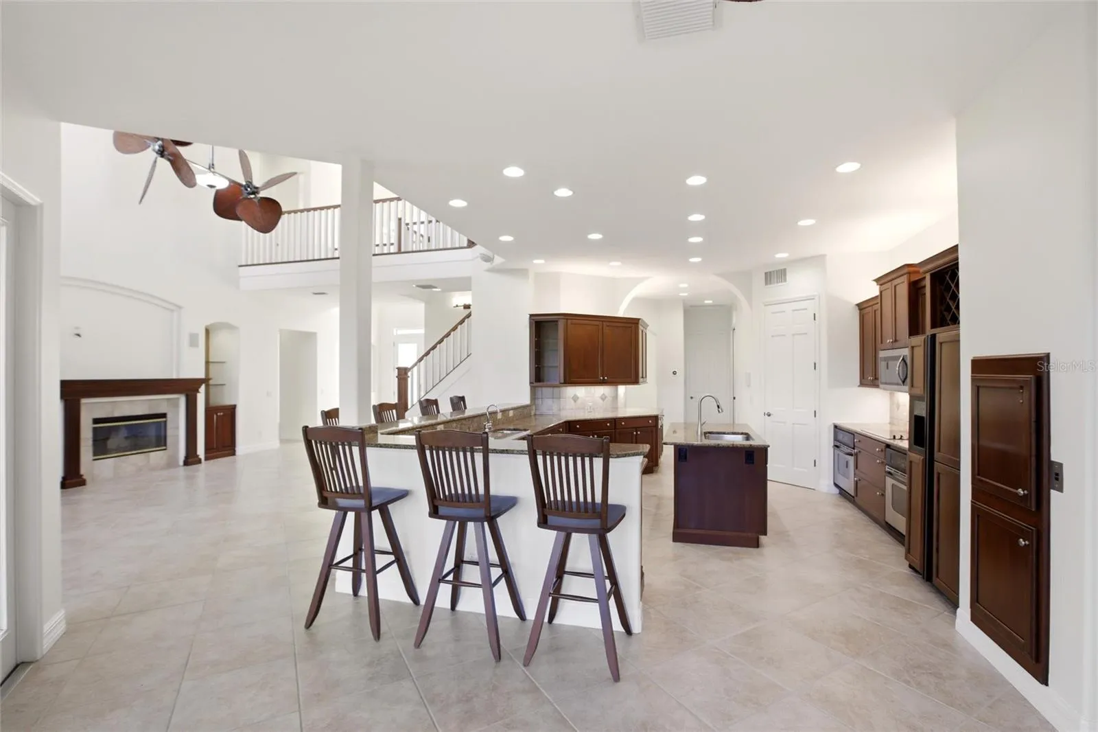 The kitchen offers an extensive breakfast bar and a comfortable casual dining area, along with generous counter space, dual sinks, double ovens, abundant cabinetry, and a spacious walk-in pantry.