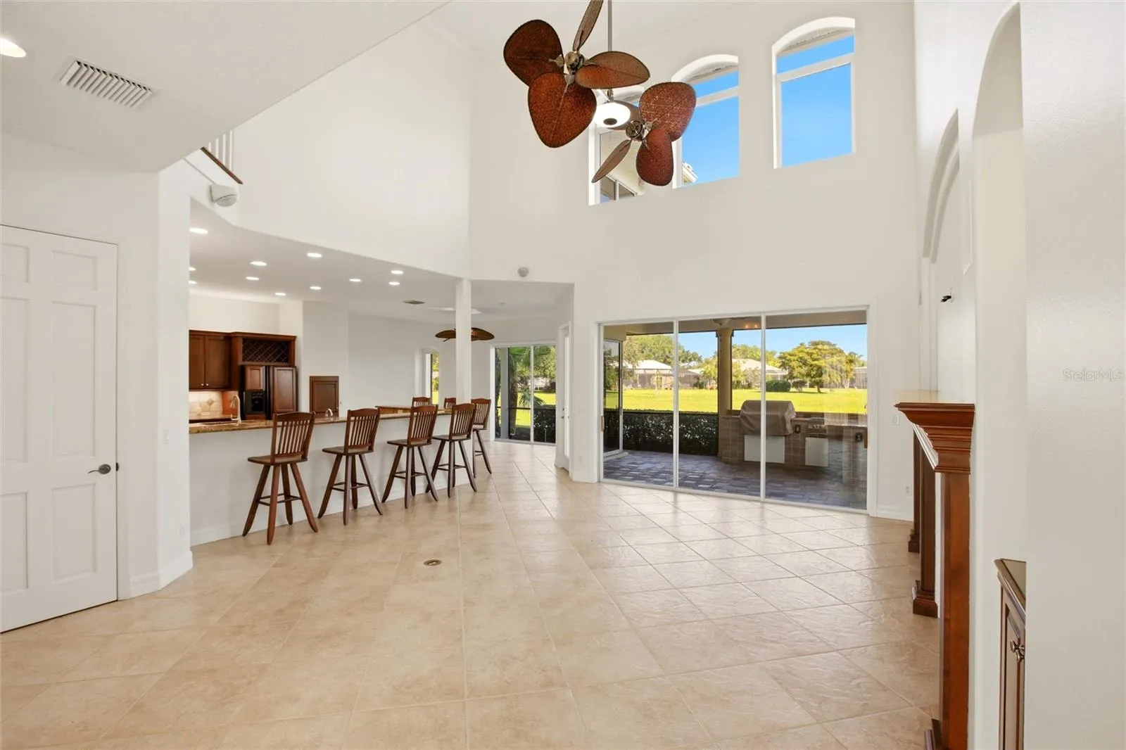The family room features soaring cathedral ceilings, a fireplace with mantel, and sliding glass doors opening to the lanai, while flowing seamlessly into the kitchen for comfortable everyday living and entertaining.