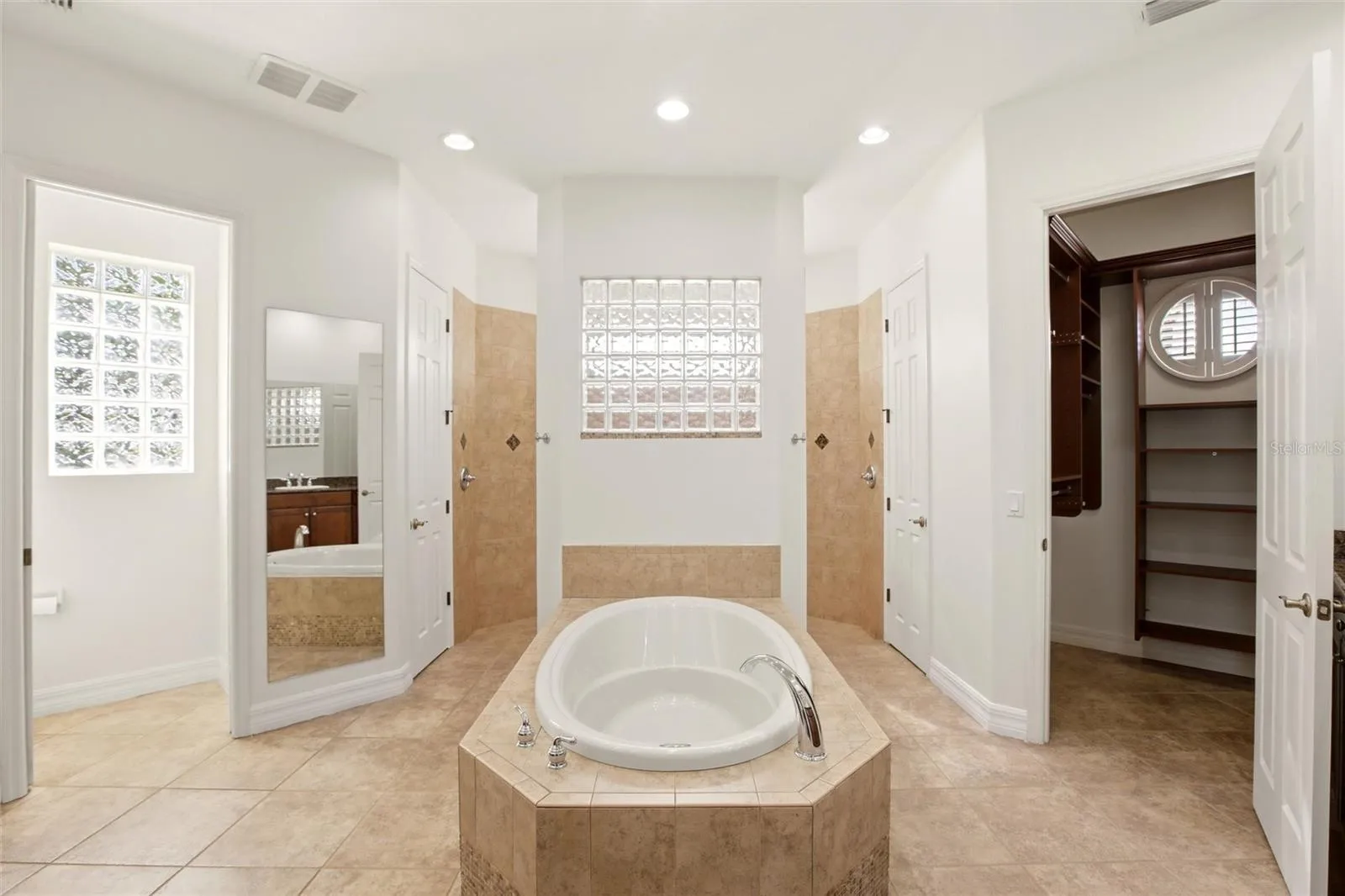 The primary bathroom features a soaking tub, split vanities with dedicated makeup counter space, a spacious walk-in shower with dual shower heads, a private water closet, and dual walk-in closets with custom organization.