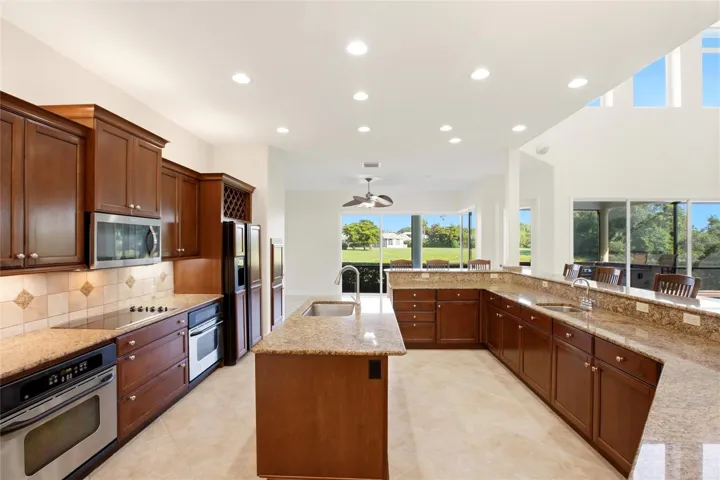 The kitchen offers an extensive breakfast bar and a comfortable casual dining area, along with generous counter space, dual sinks, double ovens, abundant cabinetry, and a spacious walk-in pantry.