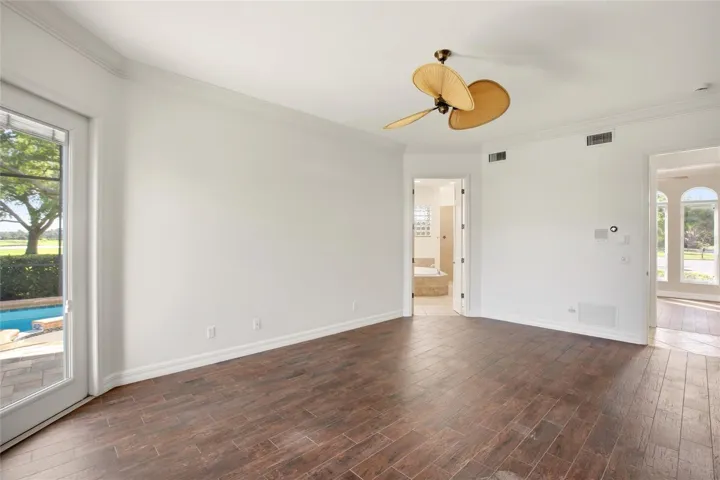 The first-floor primary suite features direct access to the lanai and showcases peaceful views of the lake and pool.