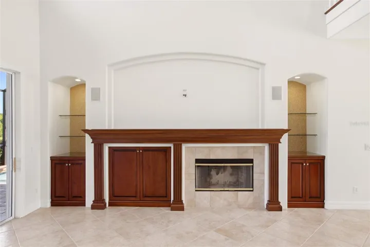 The family room features soaring cathedral ceilings, a fireplace with mantel, and sliding glass doors opening to the lanai, while flowing seamlessly into the kitchen for comfortable everyday living and entertaining.