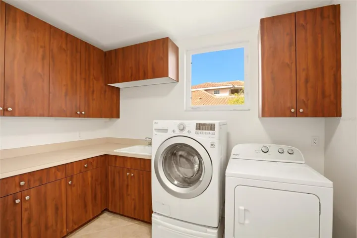 The first-floor laundry room offers abundant cabinetry, a generous folding counter workspace, and a stand-up deep freezer for added convenience and storage.