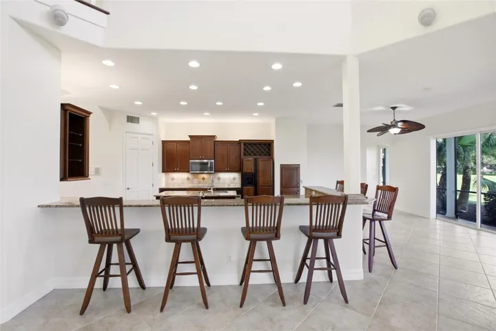 The kitchen offers an extensive breakfast bar and a comfortable casual dining area, along with generous counter space, dual sinks, double ovens, abundant cabinetry, and a spacious walk-in pantry.