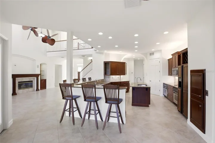 The kitchen offers an extensive breakfast bar and a comfortable casual dining area, along with generous counter space, dual sinks, double ovens, abundant cabinetry, and a spacious walk-in pantry.