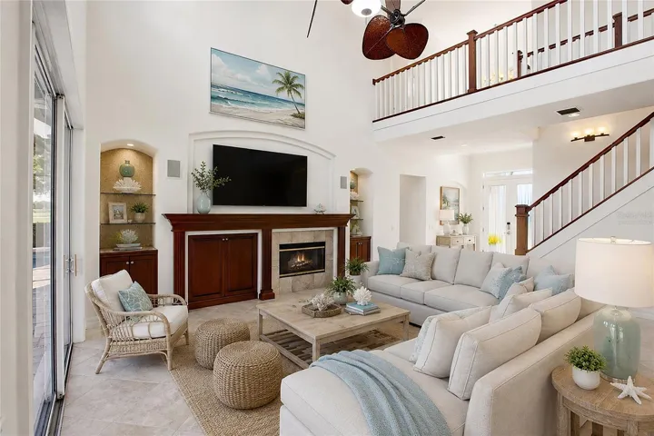 This photo is virtually staged. The family room features soaring cathedral ceilings, a fireplace with mantel, and sliding glass doors opening to the lanai, while flowing seamlessly into the kitchen for comfortable everyday living and entertaining.
