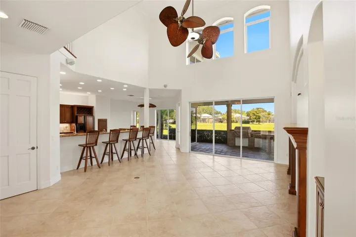 The family room features soaring cathedral ceilings, a fireplace with mantel, and sliding glass doors opening to the lanai, while flowing seamlessly into the kitchen for comfortable everyday living and entertaining.