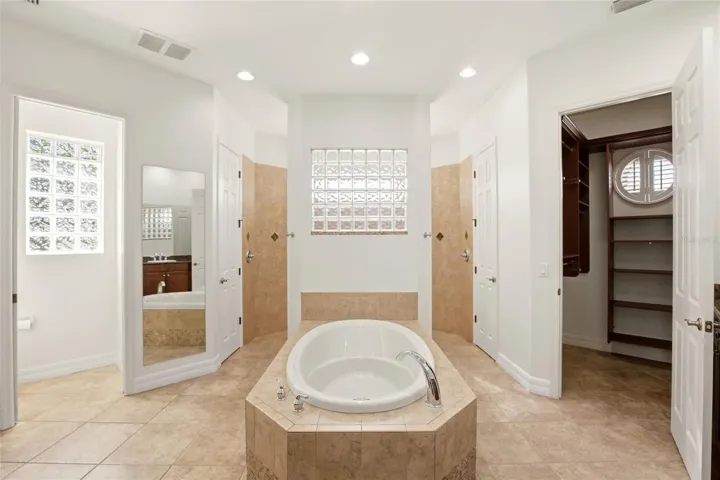 The primary bathroom features a soaking tub, split vanities with dedicated makeup counter space, a spacious walk-in shower with dual shower heads, a private water closet, and dual walk-in closets with custom organization.