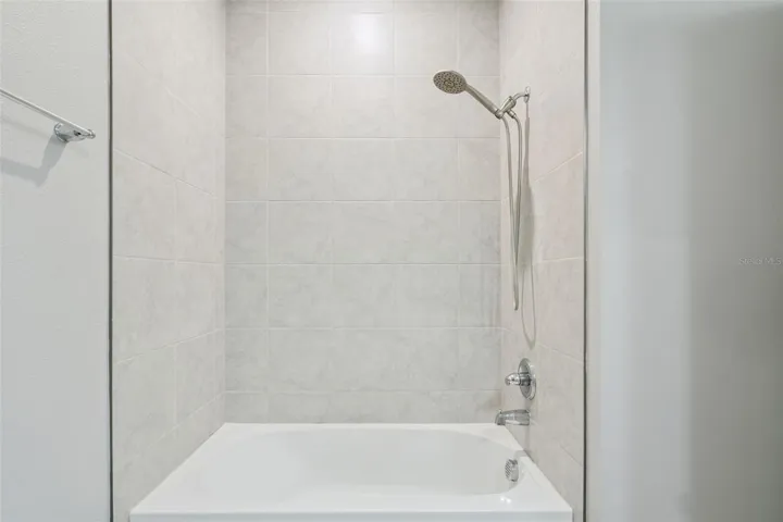 Tub with shower. Tile up to ceiling.
