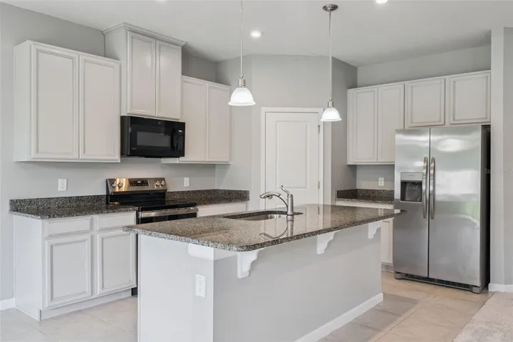 Large kitchen with stainless-steel appliances and granite countertops..
