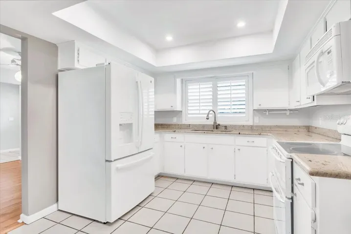Kitchen area with granite countertops and plantation style shutters.