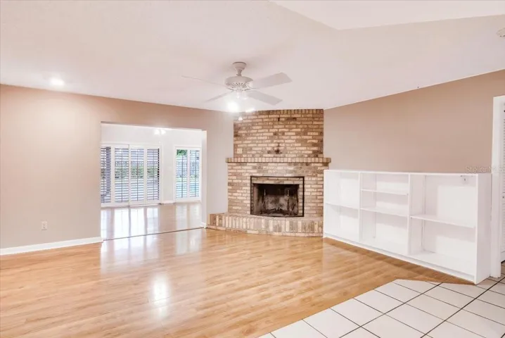 Living area to private pool area entry features brick fireplace and hardwood flooring.