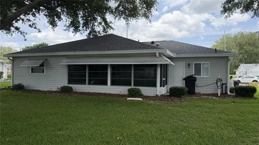 Rear exterior view with enclosed porch/lanai and shaded backyard